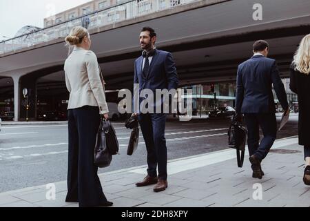 Imprenditore con borsa che parla con la collega femminile mentre si sta in piedi città Foto Stock
