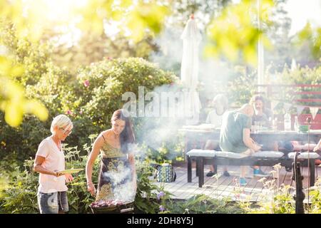 Donne mature che barbecue nel cortile posteriore il giorno di sole Foto Stock