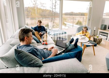 Vista ad alto angolo di padre e bambini con tecnologia wireless a casa Foto Stock