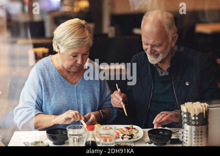 La coppia anziana mangia cibo mentre si siede al ristorante Foto Stock