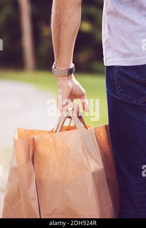 Immagine ritagliata di un uomo che porta borse marroni Foto Stock