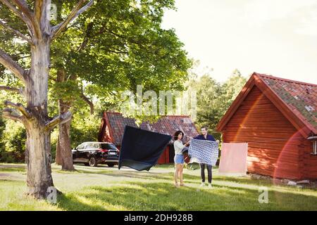 Lunghezza intera di uomo e donna che asciugano i vestiti in cortile il giorno di sole Foto Stock
