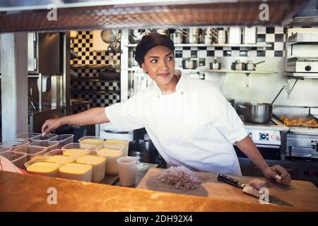 Cucina femminile chef mentre si guarda lontano alla cucina del ristorante Foto Stock