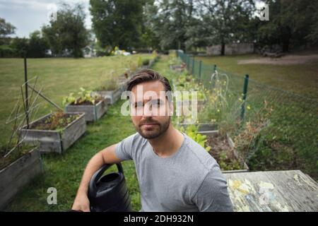 Ritratto di uomo medio adulto con annaffiatura lattina in verdura giardino Foto Stock