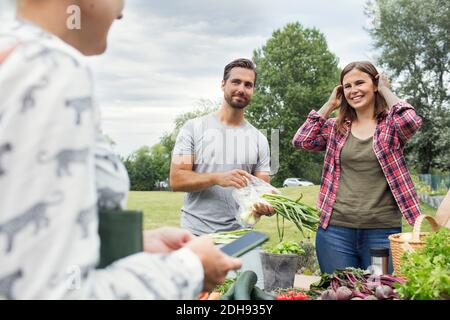 Coppia di mezza età adulta che guarda la cliente femminile in orto Foto Stock