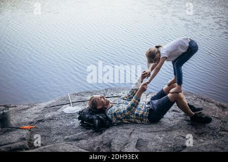 Sorridente padre che gioca con la figlia mentre si sdraia vicino al lago Foto Stock