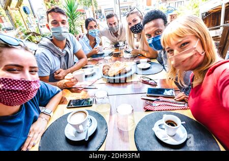 Amici che prendono selfie al caffè bar - persone che si divertono Insieme in caffetteria coperta da maschere facciali - nuovo normale concetto di stile di vita Foto Stock