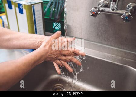 Immagine ritagliata dello chef lavando le mani in cucina commerciale Foto Stock