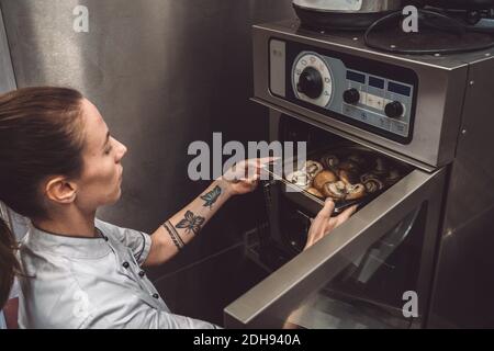 Vista ad alto angolo dei funghi da forno da chef femminile Foto Stock