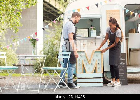 I proprietari che piazzano la lettera M fuori da un camion di cibo sulla strada Foto Stock