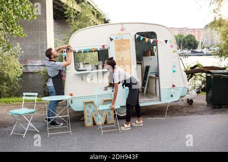 Uomini e donne che lavorano fuori camion cibo su strada Foto Stock