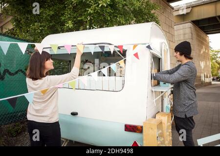 Uomini e donne che lavorano fuori camion cibo su strada Foto Stock