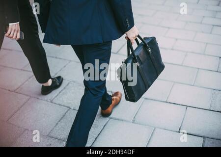 Una sezione bassa dei colleghi che camminano sul marciapiede Foto Stock