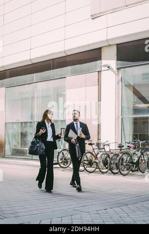 Donna d'affari con collaboratore che cammina in città Foto Stock