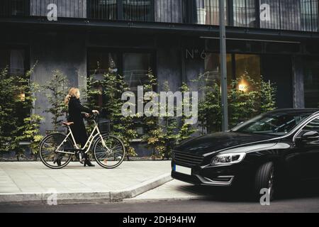 Vista laterale completa di una donna d'affari con una passeggiata in bicicletta edificio Foto Stock