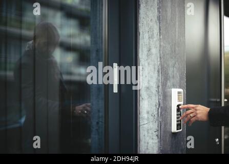 Immagine ritagliata della mano di un uomo d'affari che inserisce il codice di sicurezza per aprire porta dell'ufficio Foto Stock