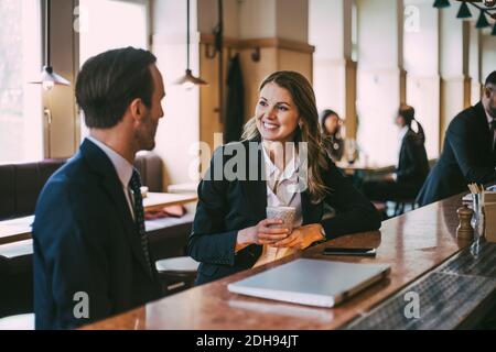 Donna d'affari sorridente che parla con un uomo d'affari nel ristorante Foto Stock