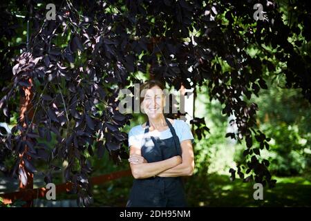 Ritratto di sicuro donna giardiniere in piedi braccia incrociate in cantiere Foto Stock