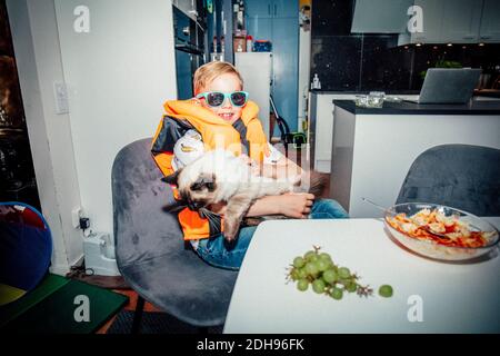 Ritratto di ragazzo sorridente con gatto al tavolo Foto Stock