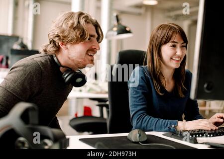 Uomini e donne sorridenti professionisti che discutono mentre si siedono in ufficio Foto Stock