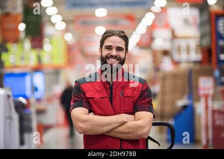 Ritratto di felice venditore in piedi braccia incrociate presso il negozio di hardware Foto Stock