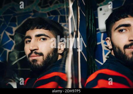 Giovane uomo che guarda attraverso specchio del bagno al ristorante Foto Stock