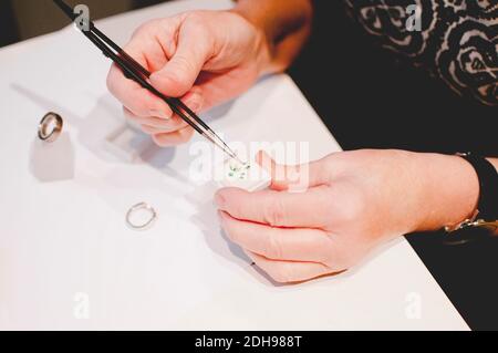 Immagine ritagliata di un'anziana persona artigiana che monta gioielli in officina Foto Stock