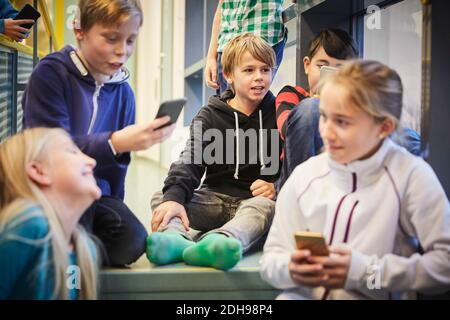 Studenti junior con telefoni cellulari a scuola Foto Stock