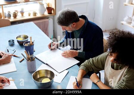 Vista ad angolo alto uomo e donna che disegnano al tavolo durante classe d'arte Foto Stock