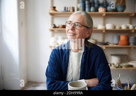 Donna matura pensierosa seduta in classe ceramica Foto Stock