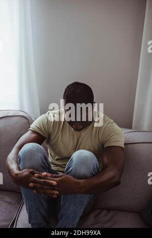 Vista ad alto angolo del triste uomo seduto sul divano casa Foto Stock