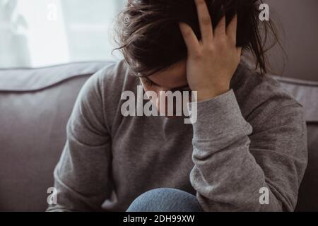 Primo piano di una donna triste che ha mal di testa mentre si siede a casa Foto Stock