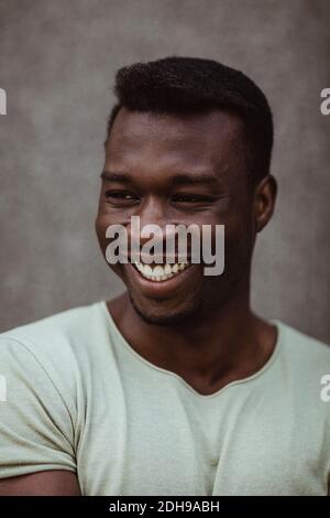 Primo piano di un uomo felice che guarda lontano mentre si trova in piedi all'aperto Foto Stock