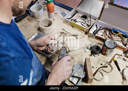 Vista ad angolo alto del proprietario che fa occhiali con l'attrezzatura in officina Foto Stock