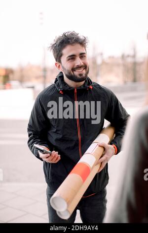 Sorridente giovane delivery man che consegna il pacchetto Foto Stock