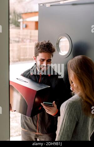 Cliente femminile che riceve il pacco dal consegnatore Foto Stock