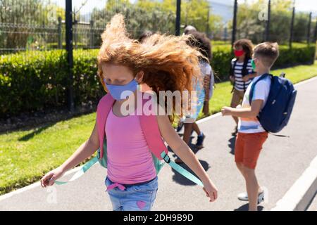 Gruppo di bambini che indossano maschere a piedi sul sentiero Foto Stock