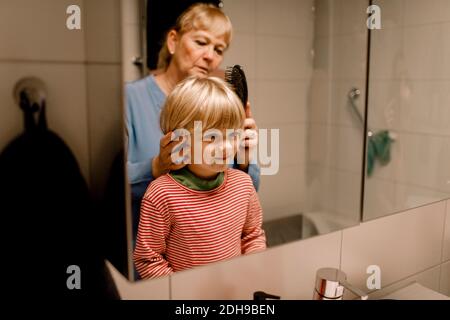 Donna anziana che combatte i capelli del nipote in bagno a casa Foto Stock