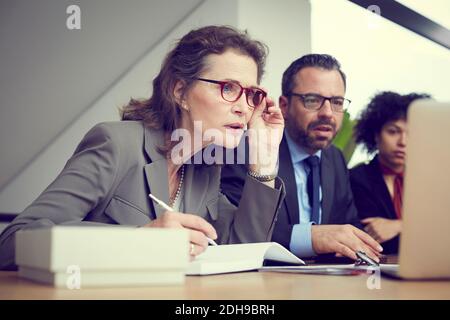 Donna giurista fidata che siede da colleghi in ufficio Foto Stock