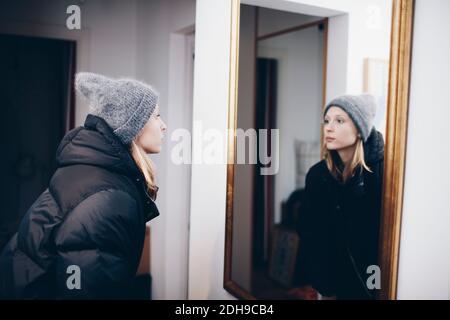 Donna che guarda la riflessione nello specchio sulla parete Foto Stock