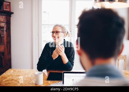 Donna felice seduta di fronte all'uomo che guarda via casa Foto Stock