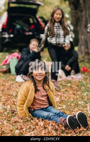 Ritratto di sorridente ragazza seduta sulle foglie d'autunno durante il picnic Foto Stock