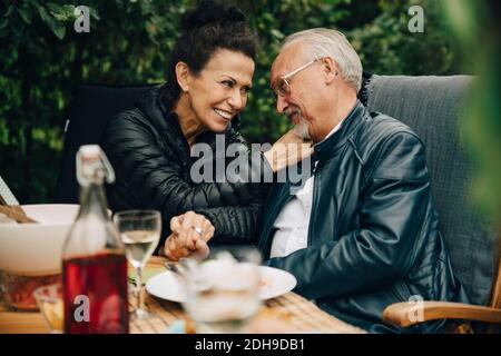 Felice uomo anziano e donna che tiene le mani mentre si siede a. tavolo da pranzo Foto Stock