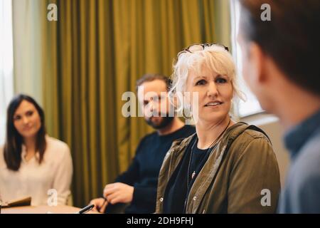 Donna d'affari sicura che discute con i colleghi nella riunione della sala riunioni Foto Stock