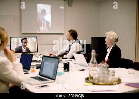 Professionisti di affari di sesso maschile e femminile che discutono in una videoconferenza globale in sala riunioni Foto Stock