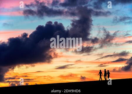 Sagome di tre ragazze che camminano al tramonto, Puerto de la Cruz, Spagna Foto Stock