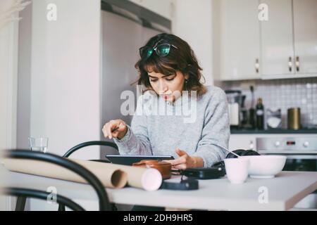 Donna che legge sul tablet che lavora da casa Foto Stock