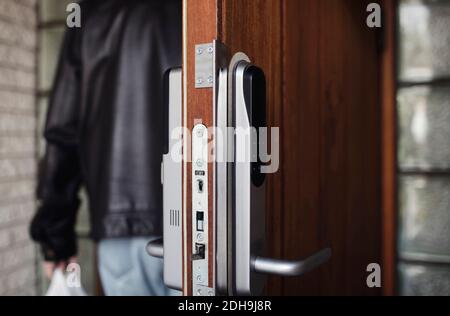 Primo piano della serratura moderna sulla porta con l'uomo anziano dentro sfondo Foto Stock