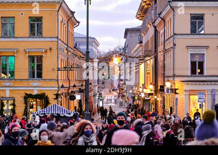 Helsinki, Finlandia - 22 novembre 2020: I popoli vestiti nella maschera sulla Piazza del Senato durante la seconda ondata di Pandemic COVID-19. L'arredamento della strada Foto Stock