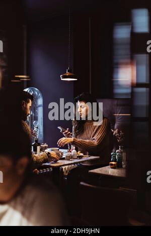 Donna che usa il telefono cellulare mentre si colazione con il ragazzo hotel Foto Stock